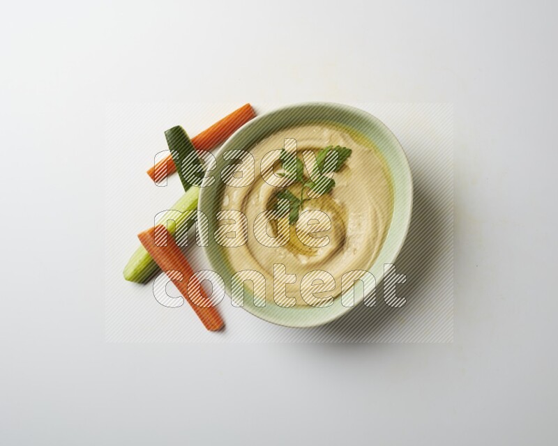 Hummus in a green plate garnished with parsley on a white background