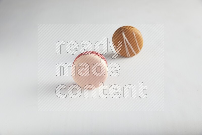 45º Shot of of two assorted Brown Irish Cream, and Pink Litchi Raspberry macarons on white background