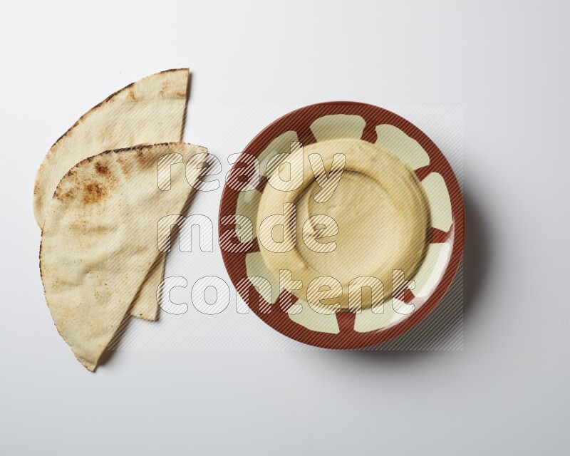 Plain hummus in a traditional plate on a white background