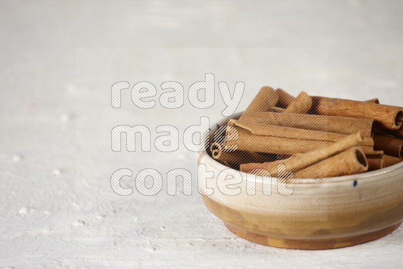 Cinnamon sticks in a ceramic bowl in different angles on white background