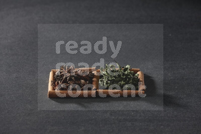 مربعان من أعواد القرفة ممتلئان باليانسون النجمي والنعناع المجفف علي خلفية سوداء