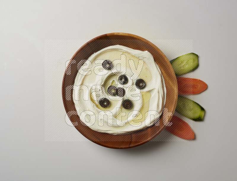 Lebnah garnished with sliced olives in a wooden plate on a white background