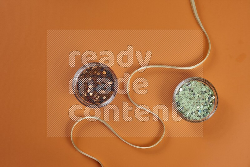 مجموعة من أدوات الخياطة والتفصيل خضراء وبرتقالية اللون على خلفية برتقالية