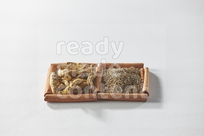 2 squares of cinnamon sticks full of cumin and turmeric fingers on white flooring