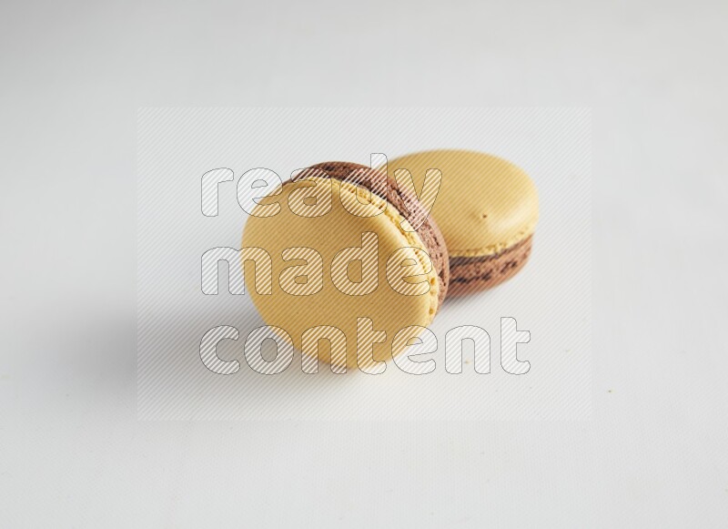 45º Shot of two Yellow and Brown Chai Latte macarons on white background
