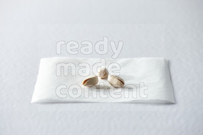 3 pistachios on a piece of paper on a white background in different angles