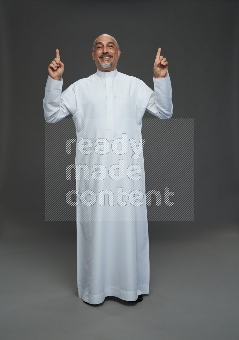 Saudi man without shomag Standing Interacting with the camera on gray background