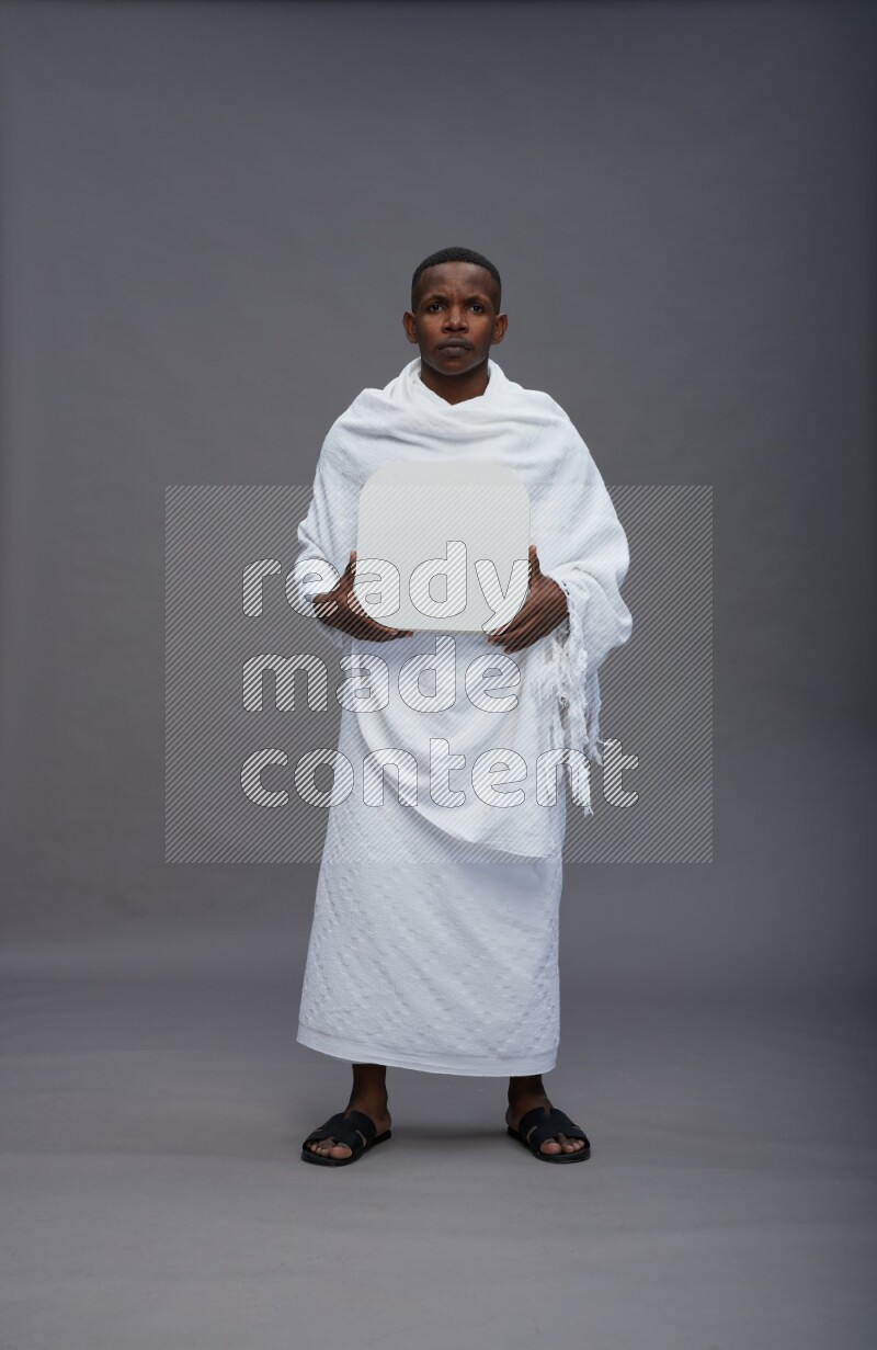 A man wearing Ehram Standing holding social media sign on gray background