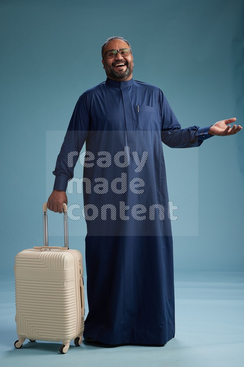 Saudi Man without shimag Standing pulling travel bag on blue background