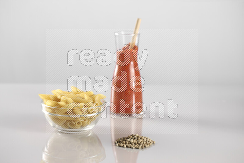 Raw pasta with tomatoe pasta with different ingredients such as cherry tomatoes, basil, garlic, bay laurel, cardamom, white pepper, black pepper, red chilis and wheat stalks on light grey background