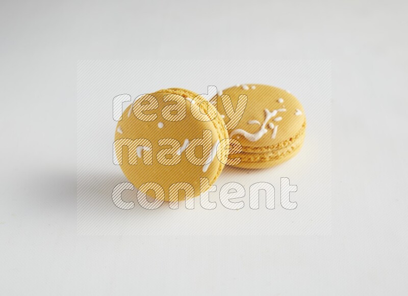 45º Shot of two Yellow Piña Colada macarons on white background