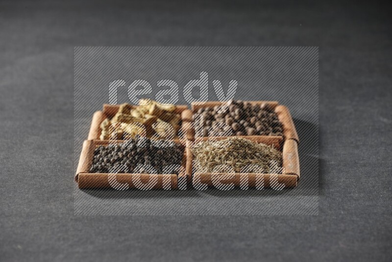 4 squares of cinnamon sticks full of black pepper, cumin, allspice and turmeric fingers on black flooring