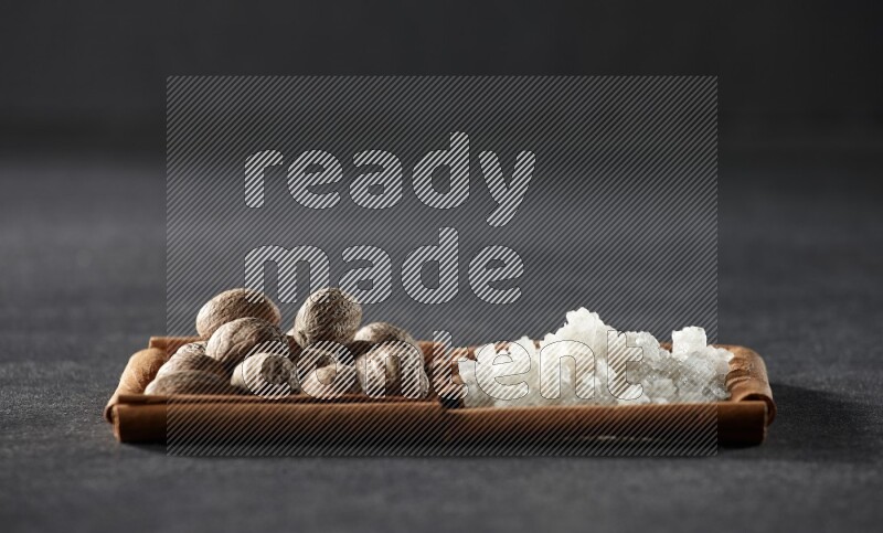 2 squares of cinnamon sticks full of nutmeg and white salt on black flooring