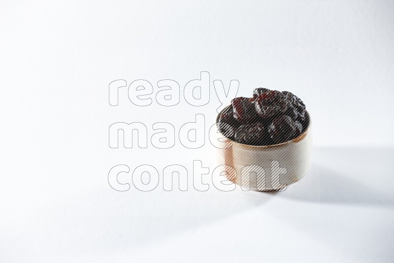 A beige ceramic bowl full of dried plums on a white background in different angles