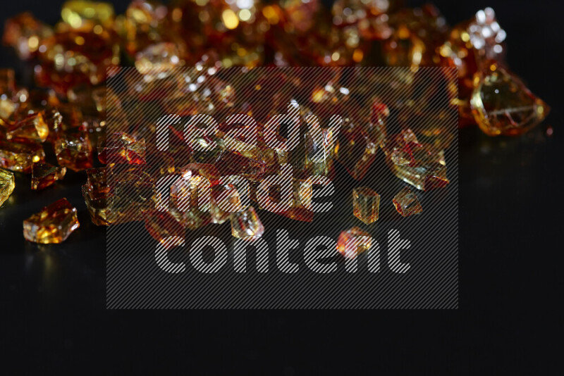 قطع زجاج برتقالية شفافة متناثرة على خلفية سوداء