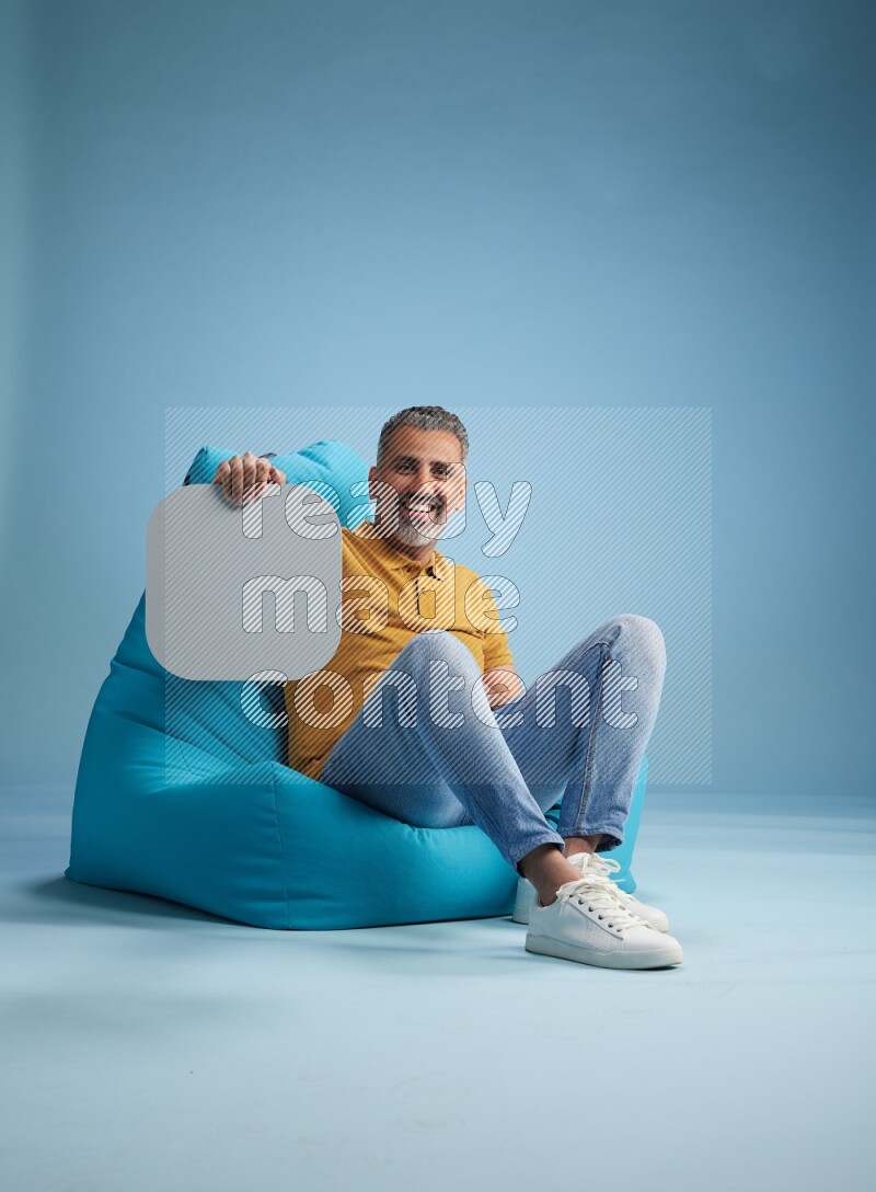 A man sitting on a blue beanbag and holding social media sign