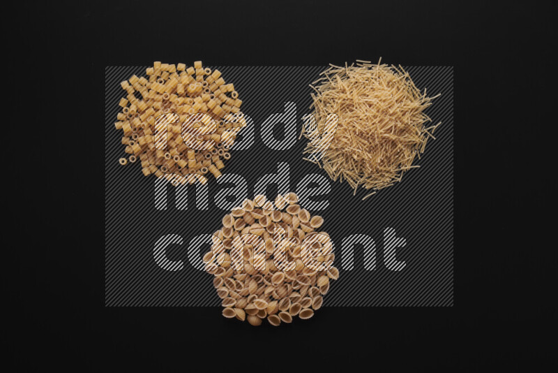 Different pasta types in bunches on black background