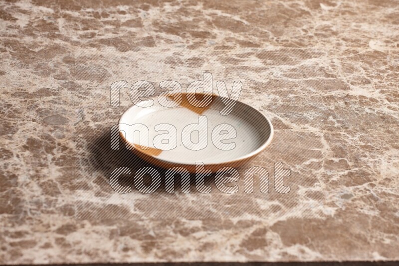 A multicolored pottery plate on beige marble background