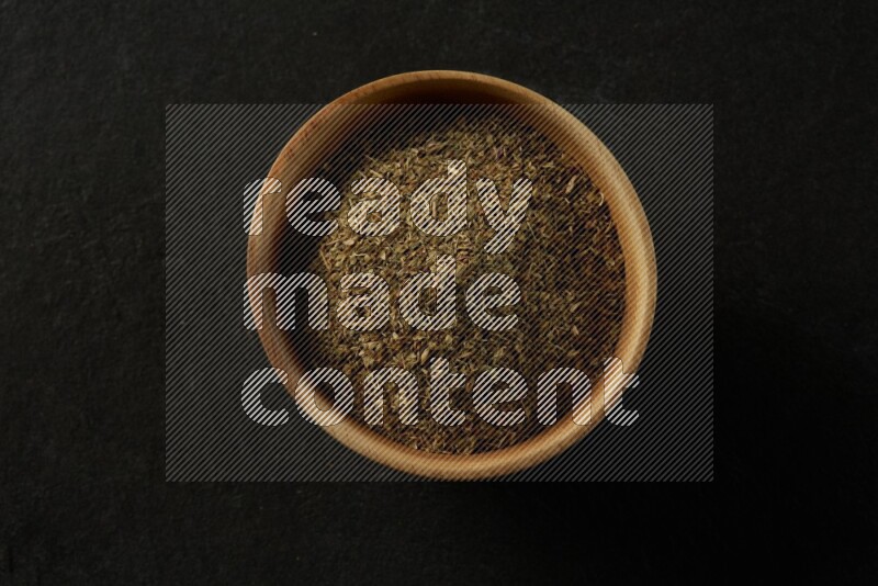 wooden round sauce bowl filled with herbs on grey textured countertop