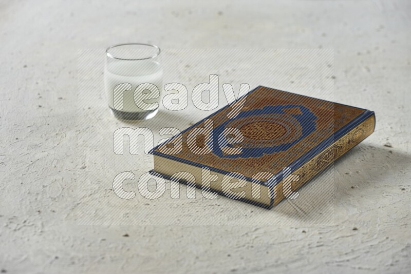 Quran with dates, prayer beads and different drinks all placed on textured white background