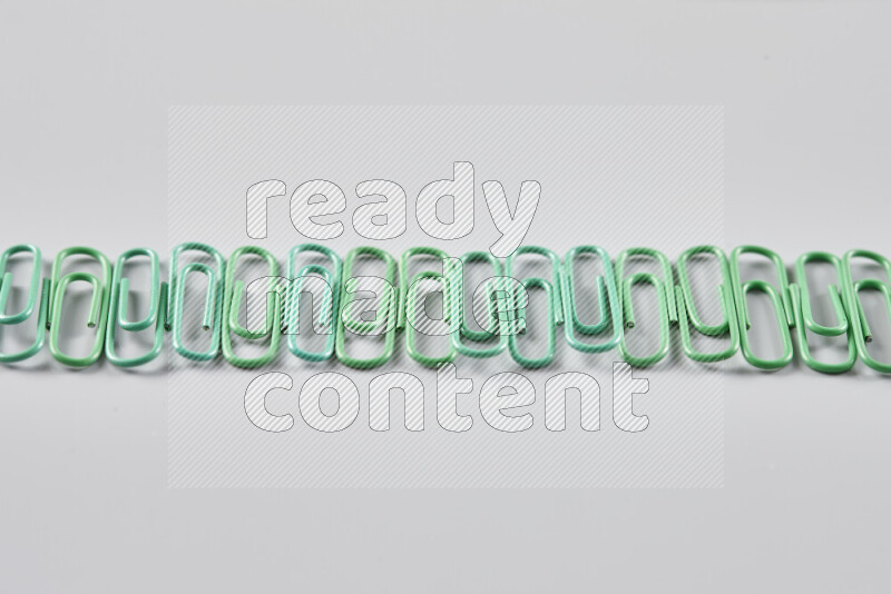 Green paper clips isolated on a grey background