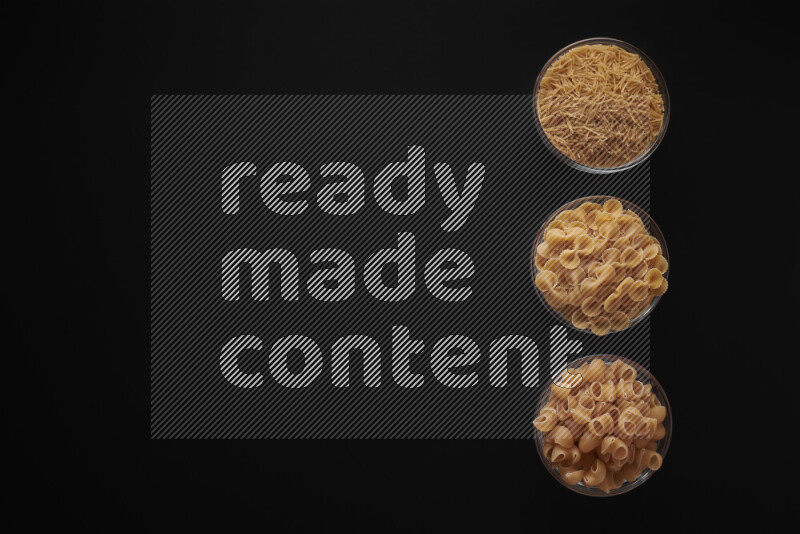 Different pasta types in 3 glass bowls on black background