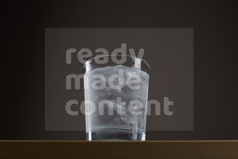 Low angle shot of a glass of water and ice on grey background