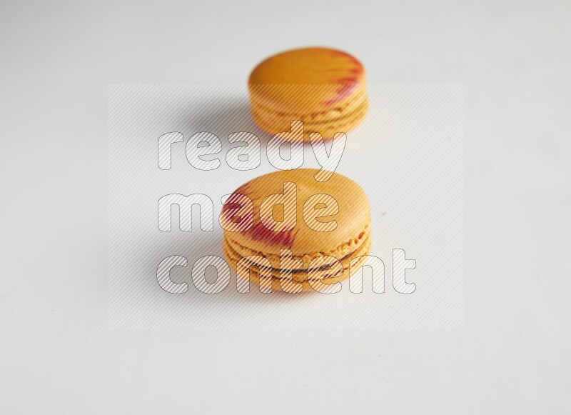 45º Shot of two orange Exotic macarons on white background