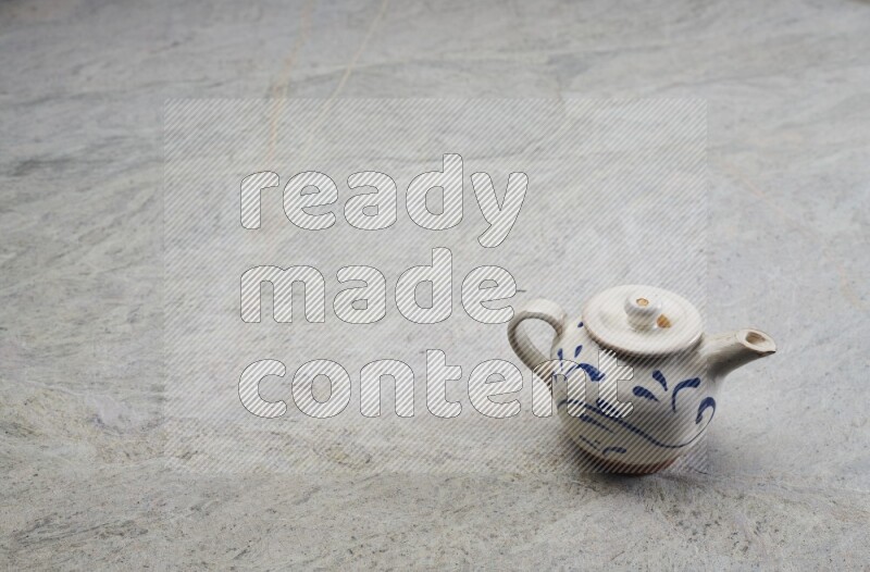 A pottery teapot on grey marble background