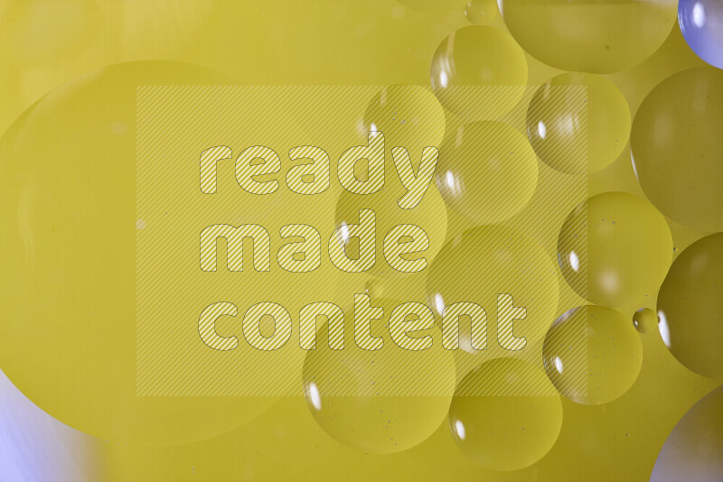 Close-ups of abstract oil bubbles on water surface in shades of yellow