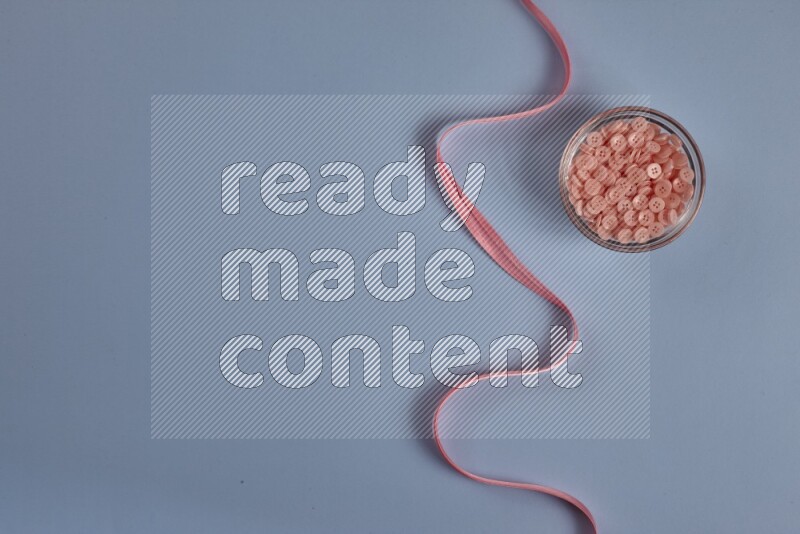 A pink collection of sewing and tailoring tools arranged on a blue background