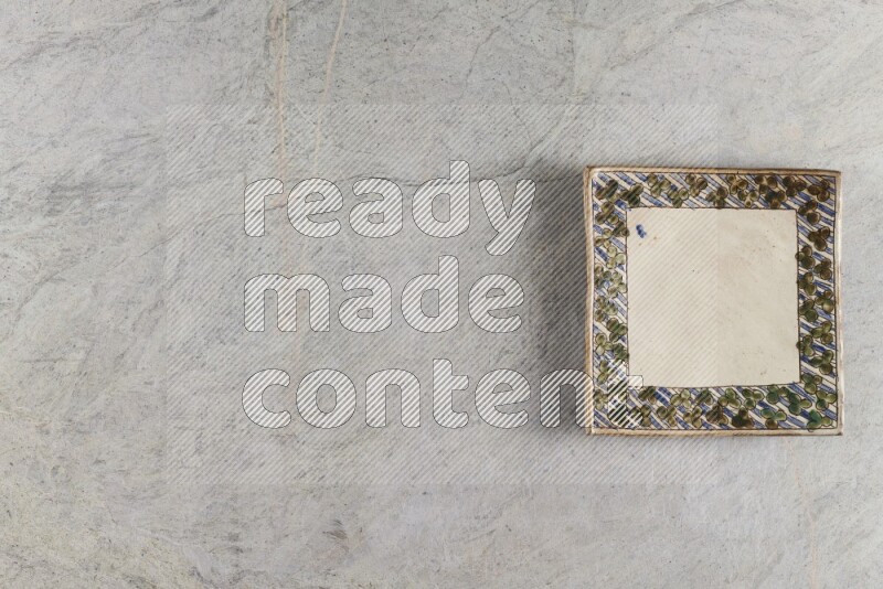 A decorative pottery plate on grey marble background