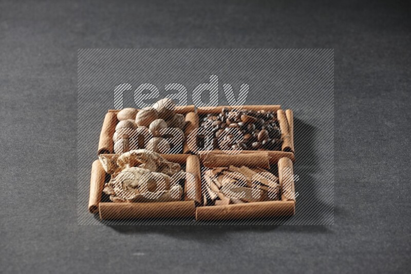 4 squares of cinnamon sticks full of coffee beans, cinnamon, dried ginger and nutmegs on black flooring