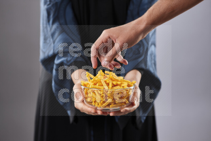 Woman in abaya holding different kinds of snacks in different positions