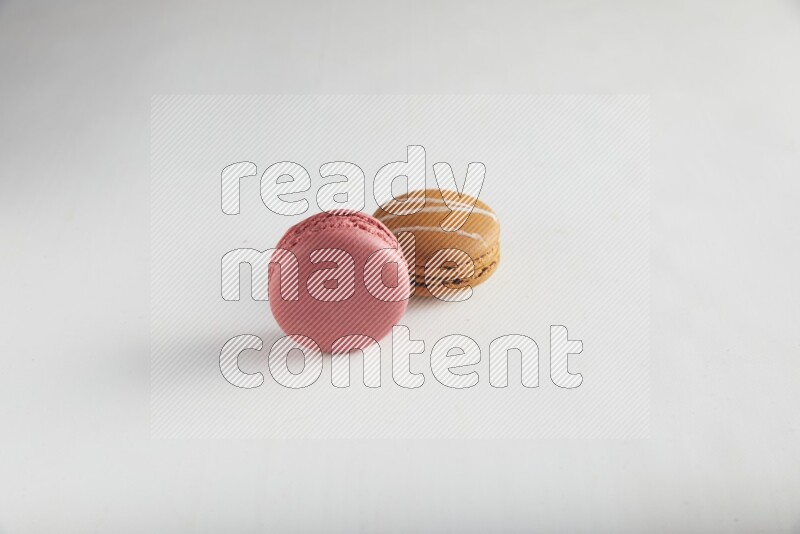 45º Shot of of two assorted Brown Irish Cream, and Pink Raspberry macarons on white background