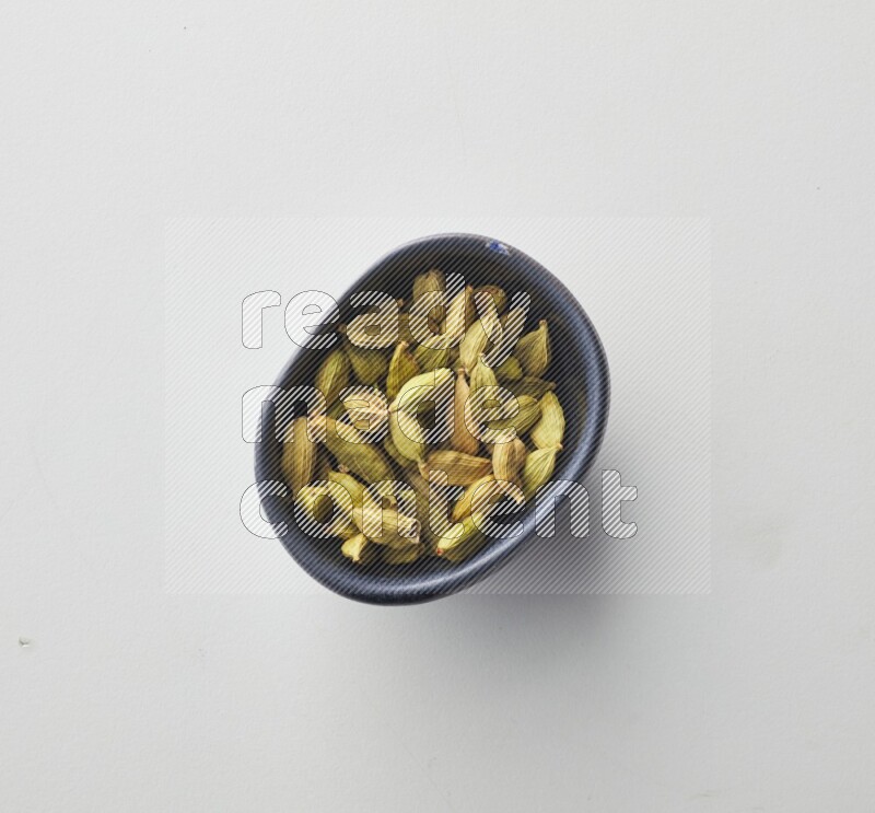Top-view shot of Cardamon in a container on white background