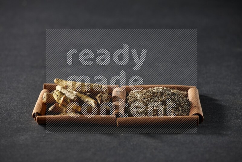 2 squares of cinnamon sticks full of cumin and turmeric fingers on black flooring