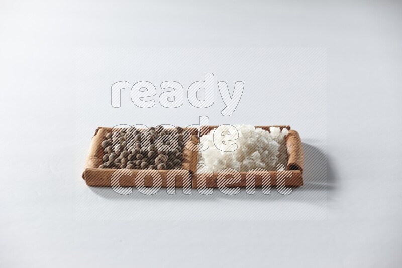 2 squares of cinnamon sticks full of white salt and allspice on white flooring