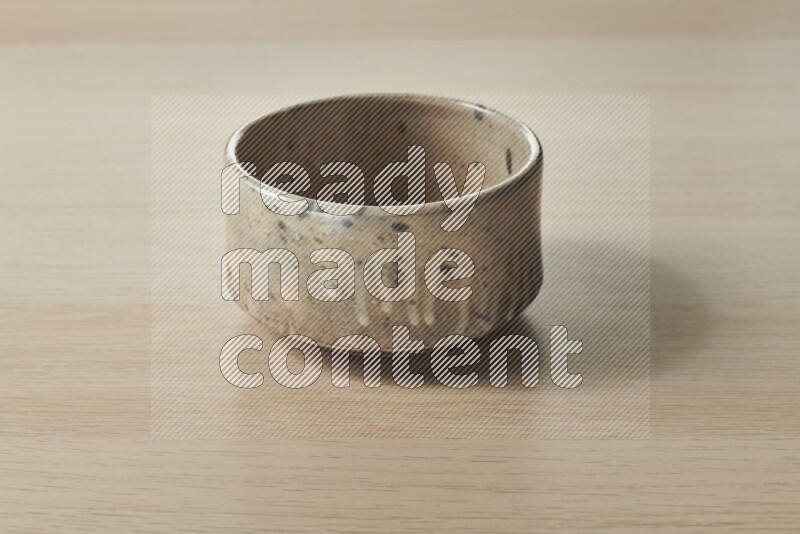 A multicolored pottery bowl on light wooden background