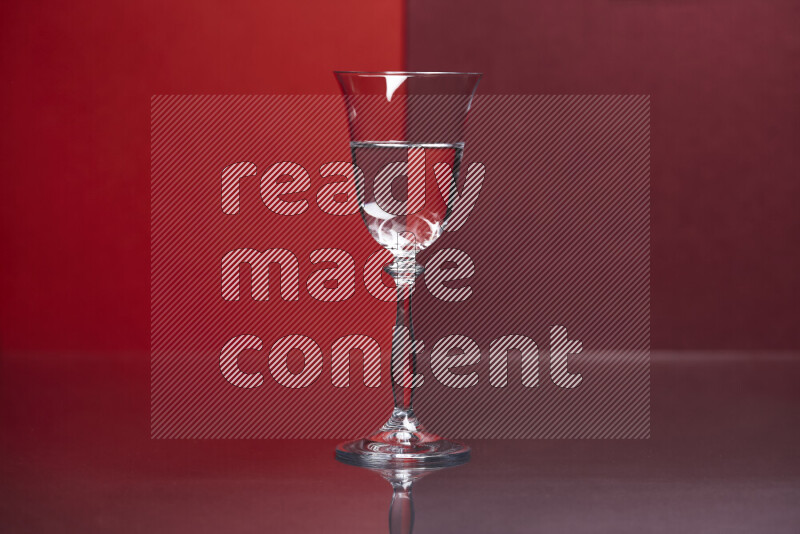The image features a clear glassware filled with water, set against red and dark red background