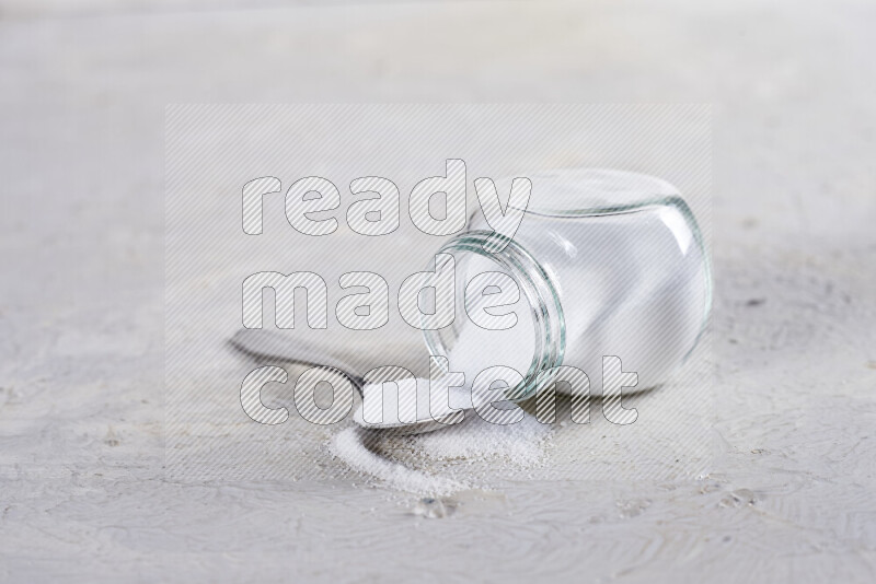 A glass jar full of fine table salt on white background