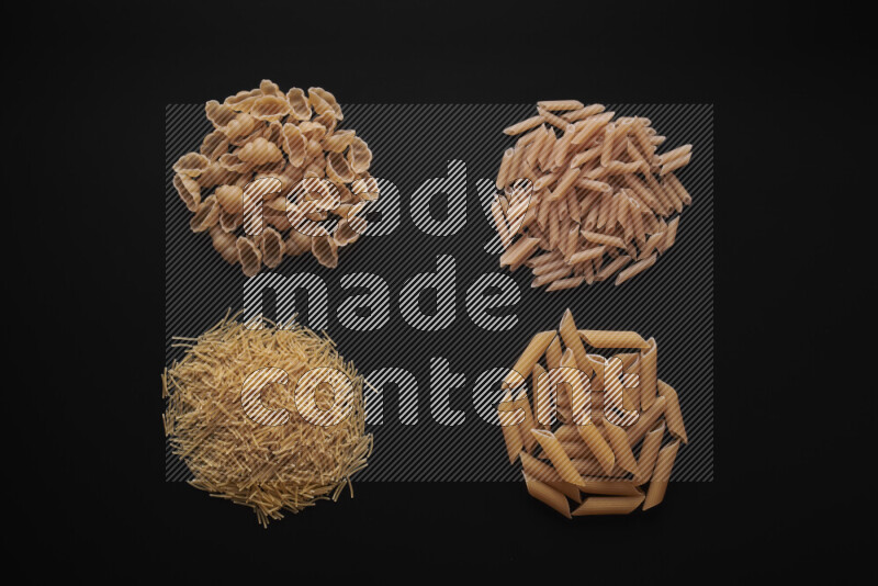 Different pasta types in bunches on black background
