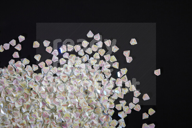 قطع صغيرة بلاستيكية ملونة للزينة متناثرة على خلفية سوداء