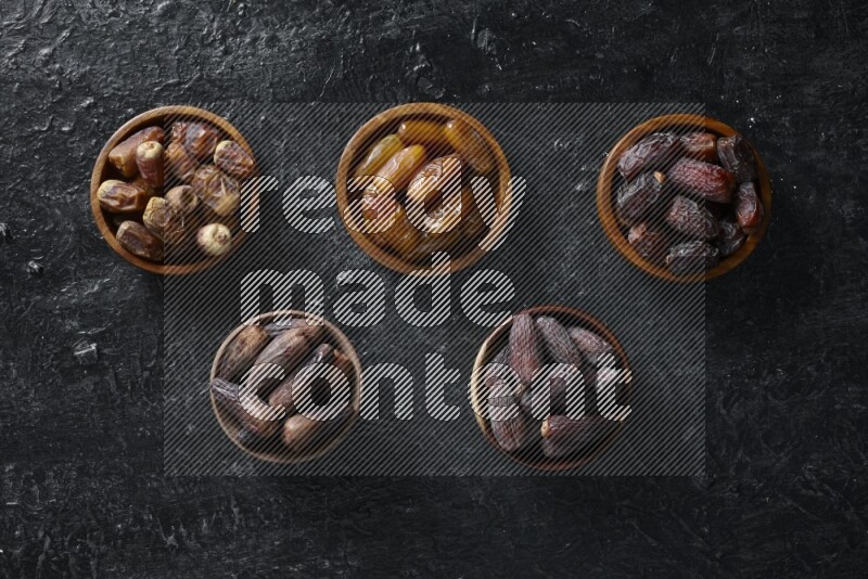Dates in wooden bowls in a dark setup