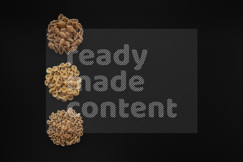 Different pasta types in 3 bunches on black background