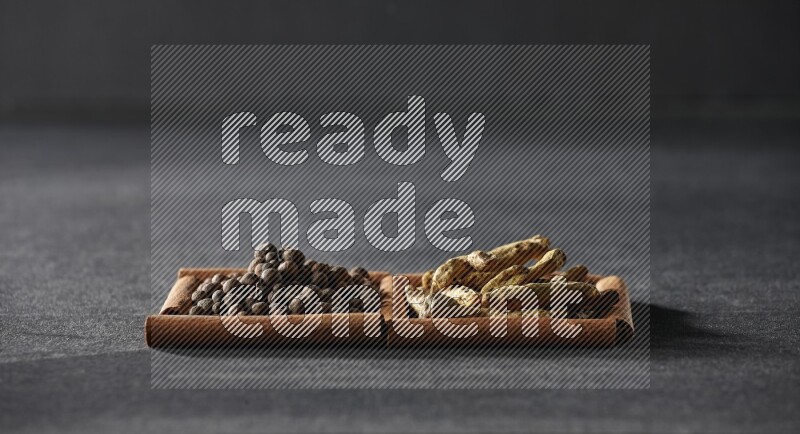 2 squares of cinnamon sticks full of allspice and turmeric fingers on black flooring