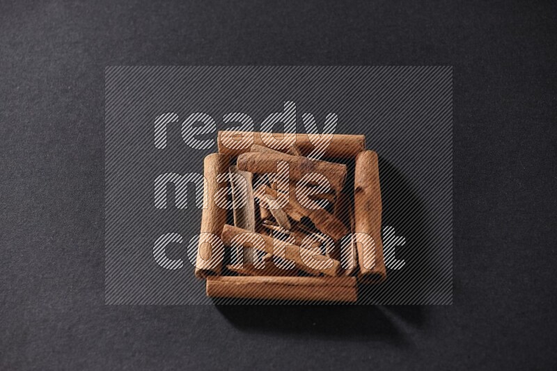 A single square of cinnamon sticks full of cinnamon on black flooring