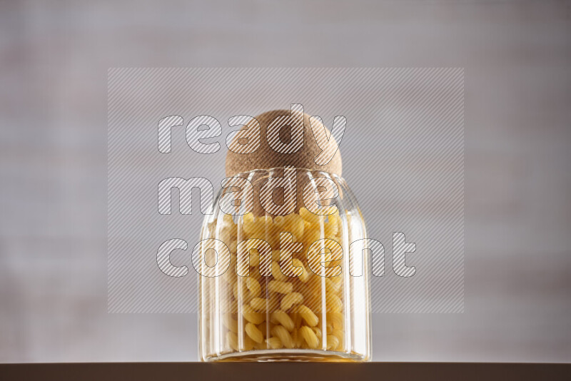 Raw pasta in glass jars on beige background