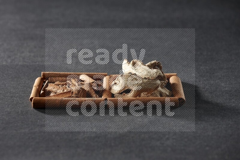 مربعان من أعواد القرفة ممتلئان بقطع من القرفة والزنجبيل المجفف علي خلفية سوداء