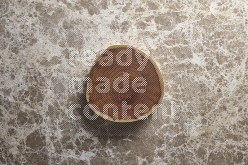 A circular wooden slab with natural textures on beige marble background